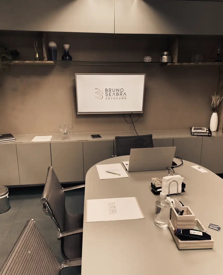 Mesa de reunião do escritório, com o logotipo Bruno Seabra Advogado na tela